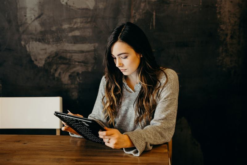 Analista revisando dados em um tablet, concentrada